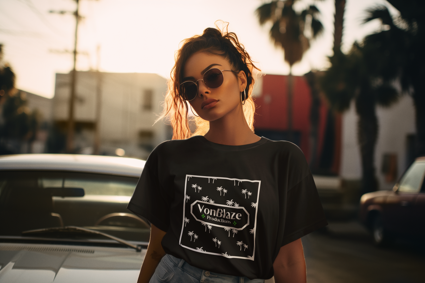 Beautiful woman standing on the street under palm trees wearing a black tshirt featuring a square VonBlaze Productions logo with a palm tree patten inside the square